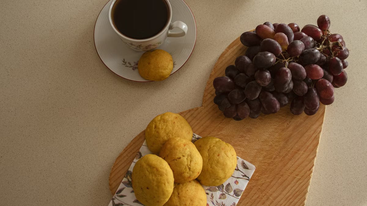A warm and inviting setup featuring coffee, cookies, and grapes on a wooden board.
